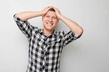 Kafaya dokunan ve sevinen gülümseyen adamın portresi, zaferi kutlayan beyaz stüdyo arka planında izole edilmiş, reklam afişi.