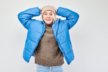 Gülümseyen sarışın genç kadının portresi. Başa dokunan ve sevinen, zaferi kutlayan beyaz stüdyo arka planında izole edilmiş, reklam pankartı.