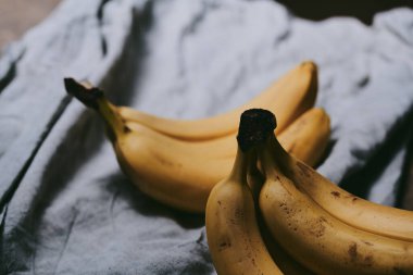 Koyu renk kumaş arka planda bir grup muzun yakın çekimi