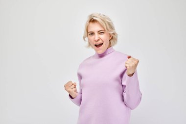 Gülümseyen sarışının portresi yumruklarını sıkan ve sevinen, zaferi kutlayan beyaz stüdyo arka planında izole edilmiş, reklam pankartı