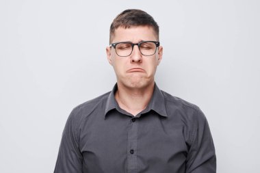 Üzgün suratlı ve beyaz arka planda ağlayan adamın portresi. Sinirler, stres, belirsizlik.