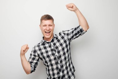 Gülümseyen adamın portresi yumruklarını sıkan ve sevinen, zaferi kutlayan beyaz stüdyo arka planında izole edilmiş, reklam afişi