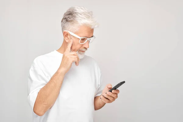 Portret Van Grijze Man Wit Shirt Kijkt Mobiele Telefoon Denkt — Stockfoto