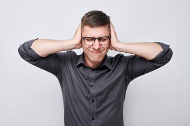 Üzgün suratlı, beyaz arka planda duygusal çöküntü hisseden yorgun adamın portresi. Sinirler, stres, belirsizlik.