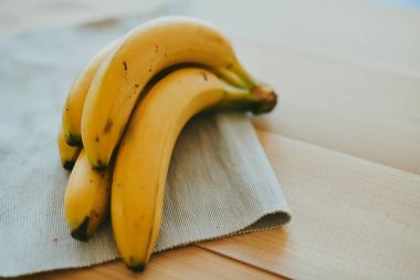 Ahşap mutfak masasında bir grup muzun yakın plan fotoğrafı.