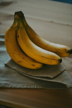 Ahşap mutfak masasında bir grup muzun yakın plan fotoğrafı.