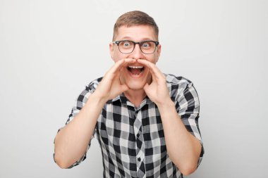 Beyaz arka planda izole edilmiş megafon gibi katlanmış avuçlar, haberlerle bağıran yakışıklı bir adamın portresi.