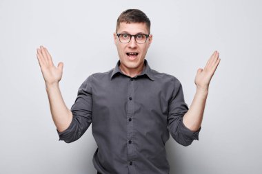 Portreci adam mutlu bir şekilde gülümsüyor avuçlarını kaldırmış ve şok olmuş bir şekilde beyaz stüdyo arka grubunda izole edilmiş bir şekilde ağzı açık.