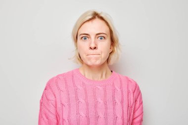 Üzgün yüzlü ve beyaz arka planda ağlayan bir kızın portresi. Sinirler, stres, belirsizlik.