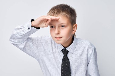 Gömlekli ve kravatlı genç adam, mesafeye bakıyor, alnında el yazısı, gri arka planda izole edilmiş.