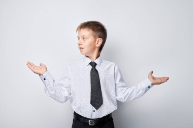 Gömlekli ve kravatlı genç, elleri havada, arka planda izole bir şekilde belirsizlik gösteriyor..