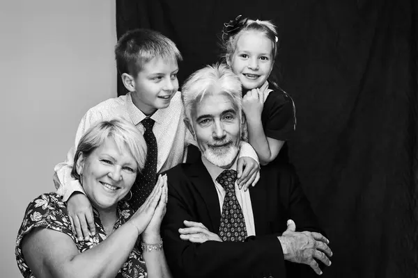 Happy family portrait in black and white grandparents with grandchildren smiling and embracing