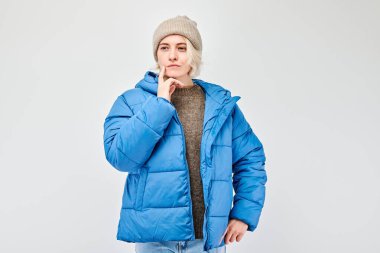 Kış kıyafetli kadın, derin bir ifadeyle, izole bir arka planda..