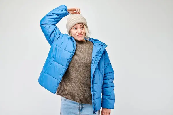 stock image Woman in winter attire with pensive expression, thinks, chooses isolated on light background