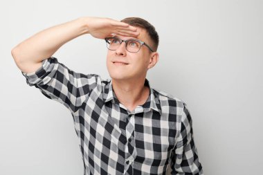 Kareli tişörtlü bir adam alnında beyaz bir arka planla yüzünü çeviriyor..