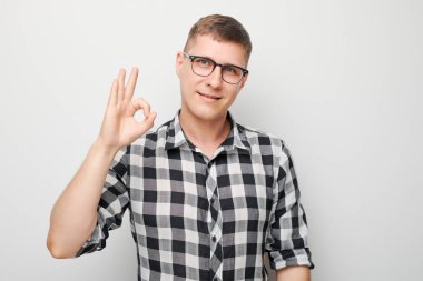 Kareli gömlekli neşeli adam beyaz arka plandaki kameraya gülümsüyor.