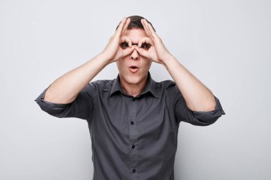 Kareli tişörtlü neşeli adam, beyaz arka plandaki kameraya gülümsüyor.