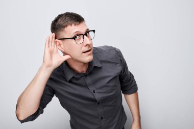 Avucunu kulağına yakın tutan bir adamın portresi, kulak misafiri olduğu beyaz arka plan.