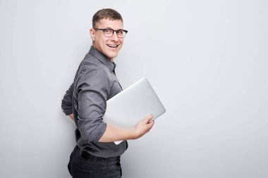 Neşeli bir iş adamı olan programcı elinde bir dizüstü bilgisayarla beyaz bir arkaplanda gülümsüyor..