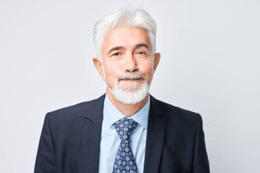 Beyaz bir arkaplanda gülmemeye çalışan kendinden emin kıdemli iş adamı..