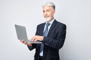 Üst düzey işadamı beyaz arka planda dizüstü bilgisayar kullanıyor.