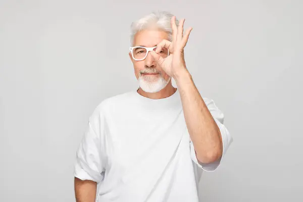 Gözlüklü Yaşlı Adam Gri Arka Planda Iyi Bir Jest Yapıyor — Stok fotoğraf
