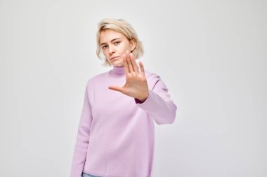 Pembe elbiseli kadın beyaz arka planda koluyla dur hareketi yapıyor..