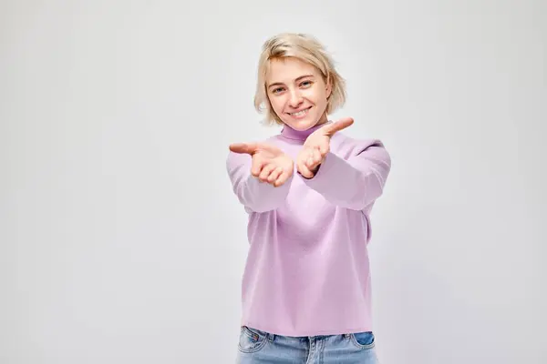 Glimlachende Jonge Vrouw Een Roze Trui Houdt Handpalmen Naar Camera — Stockfoto