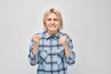 Ekose gömlekli neşeli genç kadın başarıyı kutluyor, beyaz arka planda izole edilmiş bir şekilde..