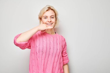 Pembe elbiseli, gülümseyen genç bir kadın bana bir jest yapıyor..