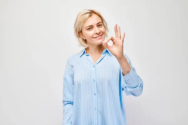 Uśmiechnięta Kobieta Niebieskiej Koszuli Paski Wykonująca Gest Dłoni Jasnym Tle — Zdjęcie stockowe