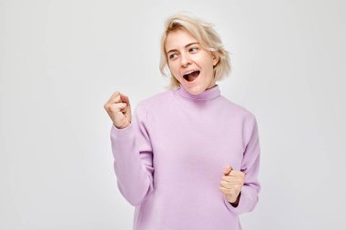 Gülümseyen sarışının portresi yumruklarını sıkan ve sevinen, zaferi kutlayan beyaz stüdyo arka planında izole edilmiş, reklam pankartı