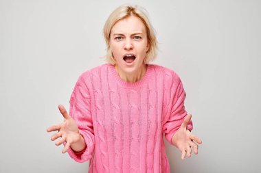 Öfkeyle bağıran, çıldıran, beyaz arka planda çöken bir kızın portresi. Depresyon, belirsizlik, sinirsel stres.