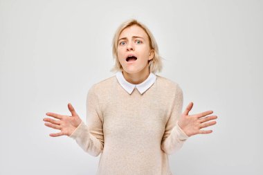 Şaşırmış genç bir kadın, ağzı açık ve ellerini kaldırmış, şokunu ve inançsızlığını ifade ediyor, arka planda izole bir şekilde..
