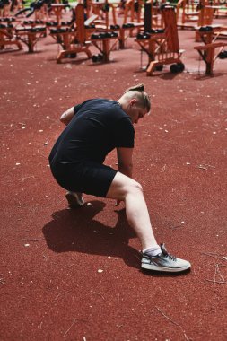 Beyaz erkek sporcu yaz parkında antrenman yapmadan önce ısınma egzersizi yapıyor.