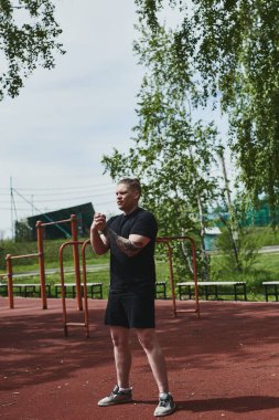 Beyaz erkek sporcu yaz parkında antrenman yapmadan önce ısınma egzersizi yapıyor.