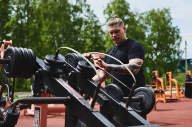 Kafkas erkek sporcu, spor aletleriyle antrenman, yaz parkında açık hava antrenmanı.