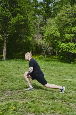 Beyaz erkek sporcu yaz parkında antrenman yapmadan önce ısınma egzersizi yapıyor.