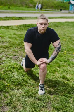 Beyaz erkek sporcu yaz parkında antrenman yapmadan önce ısınma egzersizi yapıyor.