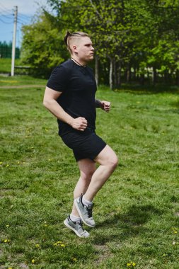 Beyaz erkek sporcu yaz parkında antrenman yapmadan önce ısınma egzersizi yapıyor.