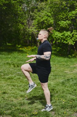 Beyaz erkek sporcu yaz parkında antrenman yapmadan önce ısınma egzersizi yapıyor.