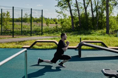 Bir erkek sporcu dışarıda spor alanında antrenman yapıyor. Beyaz erkek sporcu yaz parkında antrenman yapmadan önce ısınma egzersizi yapıyor.