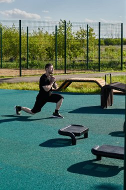 Bir erkek sporcu dışarıda spor alanında antrenman yapıyor. Beyaz erkek sporcu yaz parkında antrenman yapmadan önce ısınma egzersizi yapıyor.