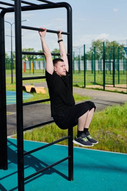 Beyaz tenli erkek sporcu, yaz parkında barfiks çekiyor.