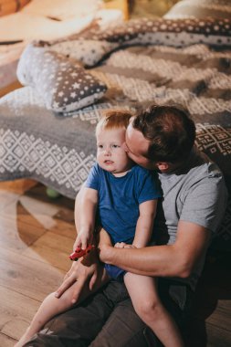 Baba ve küçük oğlu rahat bir yatakta uzanıp TV 'de film izliyorlar. Mutlu aile evde birlikte vakit geçiriyor.