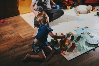 Babasıyla evde oyuncaklarla oynayan küçük bir çocuk. Mutlu baba ve oğul birlikte vakit geçiriyorlar.
