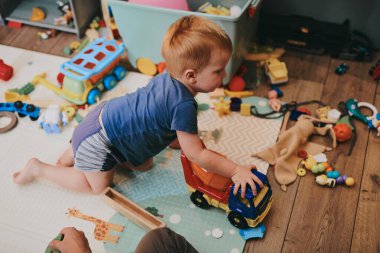 Babasıyla evde oyuncaklarla oynayan küçük bir çocuk. Mutlu baba ve oğul birlikte vakit geçiriyorlar.
