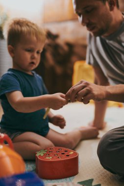 Babasıyla evde oyuncaklarla oynayan küçük bir çocuk. Mutlu baba ve oğul birlikte vakit geçiriyorlar.