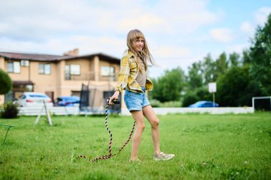 Evin bahçesinde ip atlayan mutlu kız.