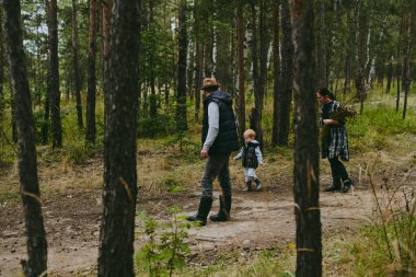 Mutlu bir aile ormanda yürüyüş yapıyor, böğürtlen ve otlar topluyor, patika boyunca seyahat ediyor ve anne ve baba ile çocukları taşlıyor.